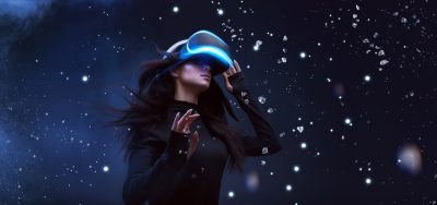 Beautiful woman with flowing hair in futuristic dress over dark background. Girl in glasses of virtual reality. Augmented reality, game, future technology concept. VR.