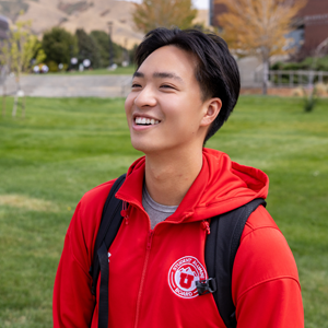 Smiling student on campus with backpack, aspiring to new heights.